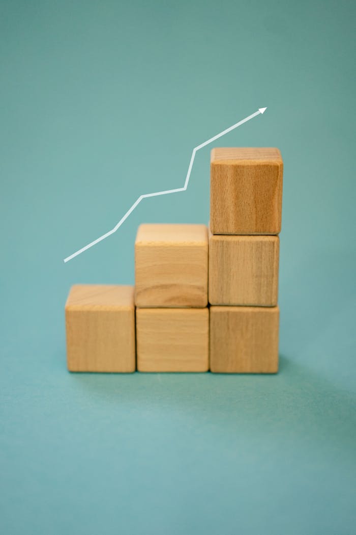 Wooden blocks forming a staircase with an upward arrow symbolizing growth and progress.